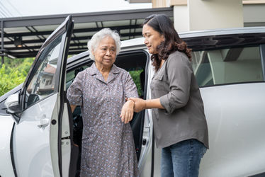 Caregiver helping elderly woman out of the car