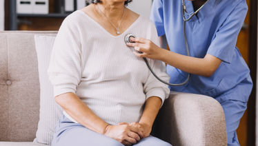 Close up of female doctor checking patient heartbeat using stethoscope during visit