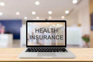Laptop computer on wood table with Health Insurance text on screen with blur hospital room background