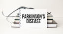 Parkinson Disease lettering on a notepad with a stethoscope and books in the background