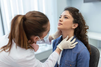 Doctor revisando el cuello de una mujer para detectar problemas de tiroides