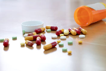 Pills and capsules spilled out on table from prescription bottle