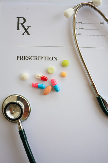 Capsules, pills, and stethoscope on a prescription script