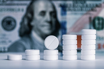 Pills stacked with hundred dollar bill background