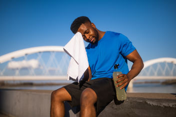 A young african-american man who wipes the sweat from his face after jogging