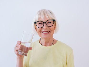 Senior woman holding glass of water and drinking water