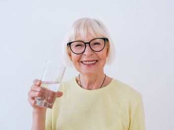 Mujer mayor sosteniendo un vaso de agua y agua potable