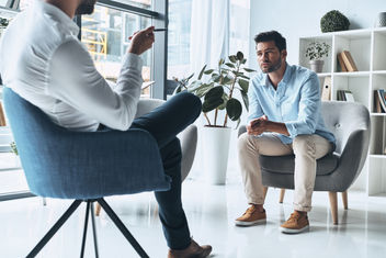 A young man solving his mental problems while having a therapy session with psychologist