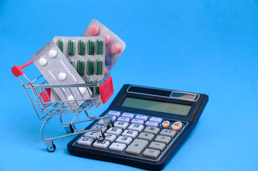 A shopping cart, calculator and pills on a blue background
