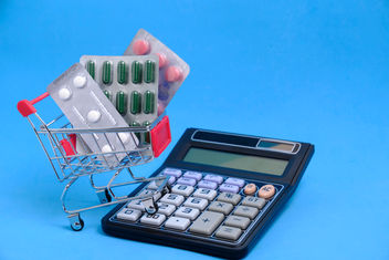 A shopping cart, calculator and pills on a blue background