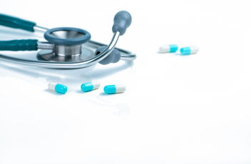 Stethoscope and blue-white capsule pills on a doctors table