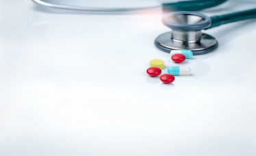 Stethoscope, capsule, and tablets pills on a physicians table