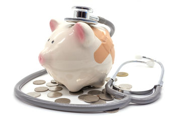 Stethoscope with pink piggy bank and coins