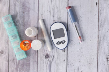 Diabetic measurement tools and medications on white wooden background