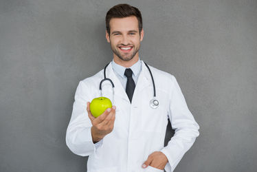 A male physician holding an apple