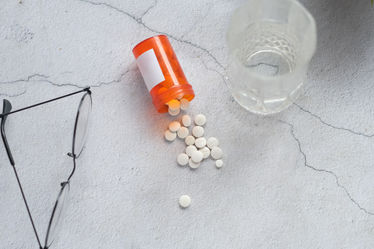 White pills on a table with a glass of water and glasses