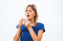 A woman with allergies and sneezing into a tissue