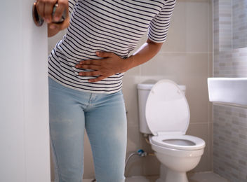 A woman standing in the bathroom holding her stomach