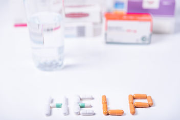 The word HELP made with medical pills and in the background several boxes of medicines