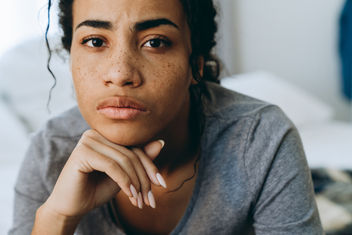 A young black woman frowning and looking at camera in bedroom