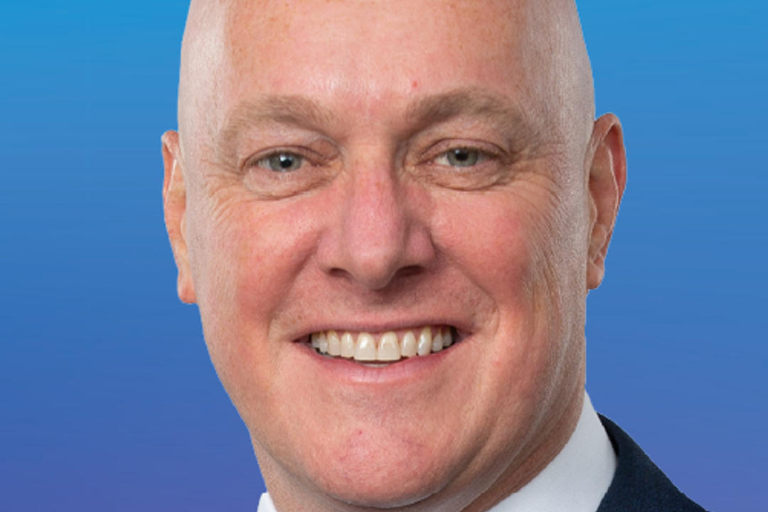 File image: Professional studio portrait of a bald man smiling against blue background