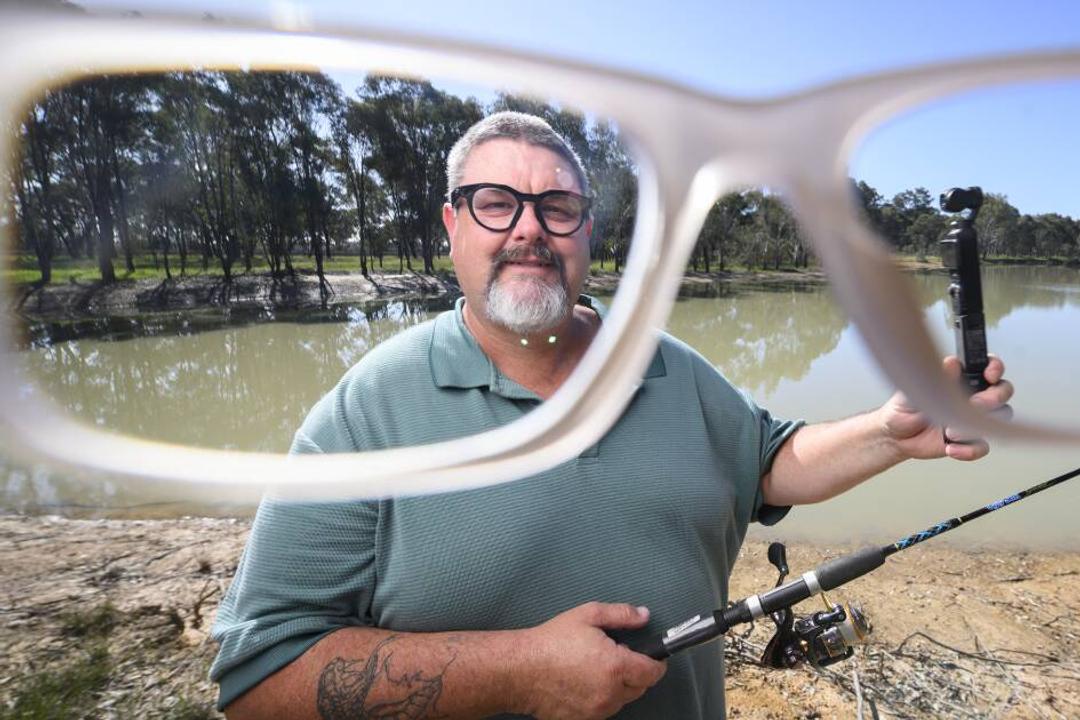Robbie Alexander. Man with fishing rod and PVC tube at Australian riverside location