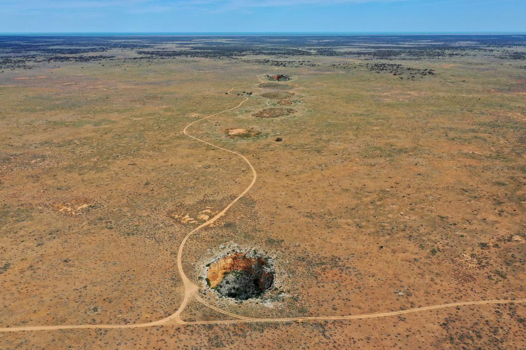 Aerial view of Australian semi-arid terrain showing winding road and rocky outcrop