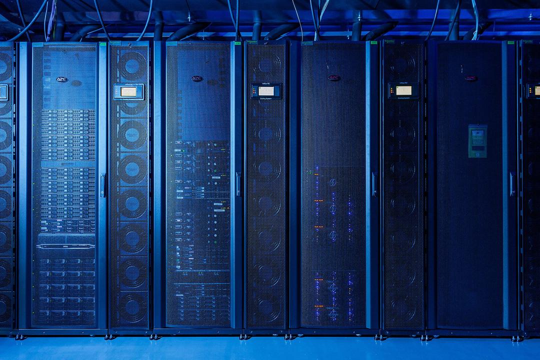 Server racks in rows with blue lighting in a data center facility.