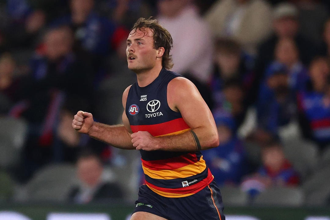 Luke Pedlar. Adelaide Crows player running with ball during AFL match, crowd in background