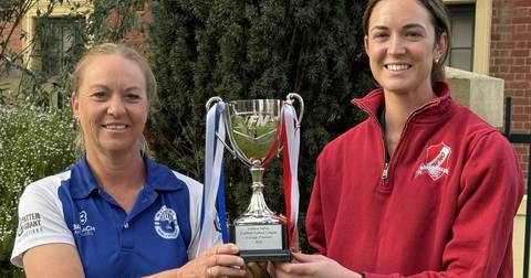 Two women hold Loddon Valley netball premiership trophy outdoors
