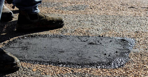 Damaged asphalt road surface showing significant cracking and deterioration