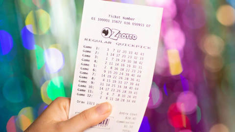 Hand holding Oz Lotto quickpick ticket with colorful bokeh background
