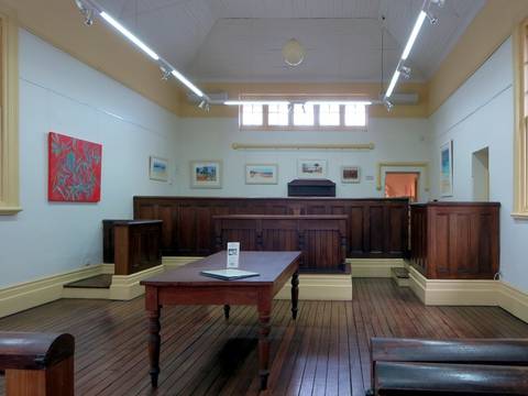 File image: Empty courtroom with wooden bench, judge's chair, and gallery seating.