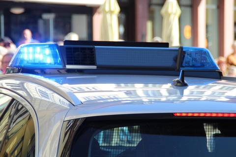 File image: Police patrol car with blue emergency lights activated on urban street with buildings visible.