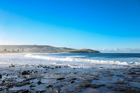 File image: Rocky coastline with breaking waves and green hills beyond