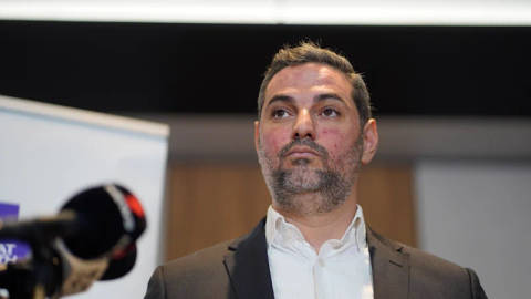 Ned Mannoun. Bearded man in brown jacket and white shirt, professional indoor portrait