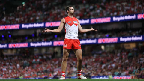 AFL player in red-and-white Swans uniform gestures during match at full stadium
