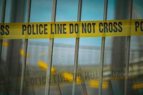 File image: Yellow police line tape on metal fence barrier.