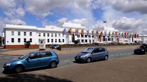 White Parliament House building with international flags, Australian government setting.