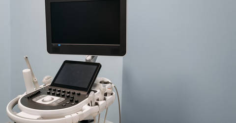 Portable ultrasound machine with monitor and control panel in medical facility.
