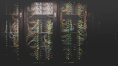 Illuminated server racks and network cables in a data center showing interconnected computing infrastructure.