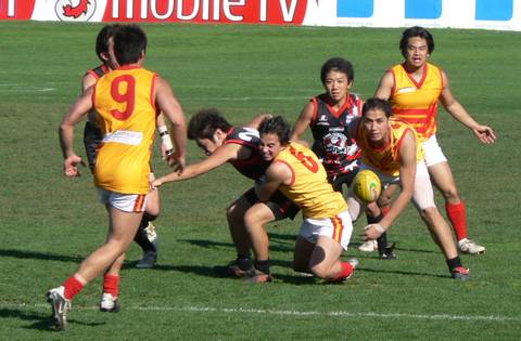 File image: AFL players in yellow-red and red-black jerseys competing for the ball with physical contact during match
