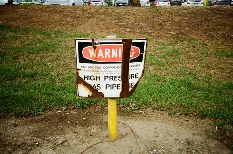 File image: Warning sign marking high-pressure gas pipe on residential lawn with yellow post