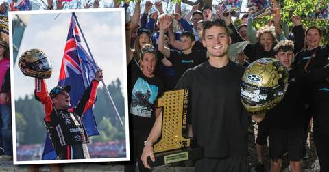 Archie McDonald. Young man holding gold Bagger Cup championship helmet and trophy, surrounded by smiling team in black shirts