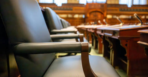 File image: Close-up of formal courtroom seating with wooden furniture and metal railings.