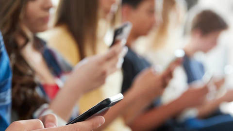 Group of young people holding mobile phones and devices together