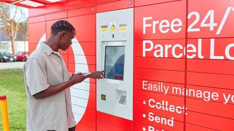 Person using touchscreen on red Australia Post Parcel Locker kiosk outdoors
