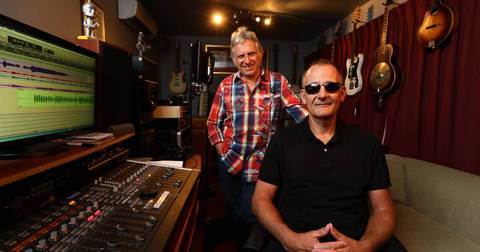 Two men in recording studio with guitars and mixing console