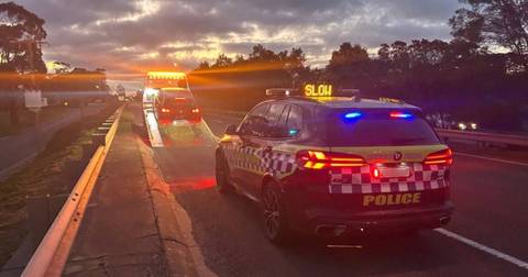 Police car and tow truck on Australian highway during evening traffic enforcement operation
