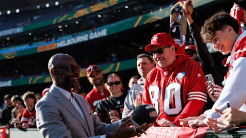 Stadium crowd at MCG during NFL game event with people in festive attire